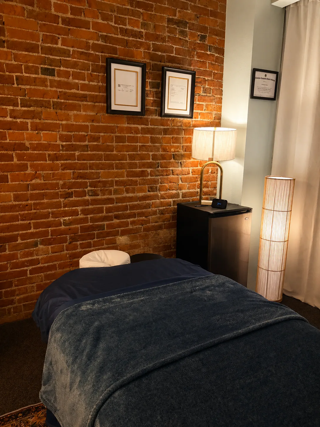 Massage table beside the exposed brick wall in the TranquiLab treatment room